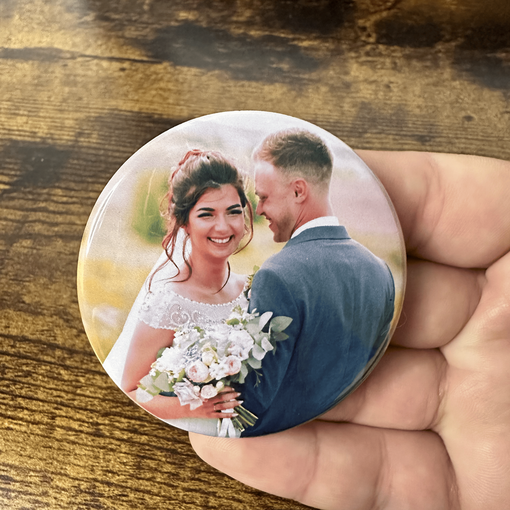Round photo magnet of a couple on a wooden surface as wedding favor