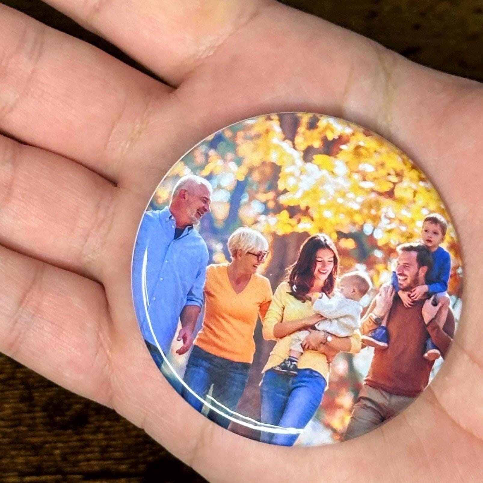 Close up: Round photo magnet held in a hand with a family picture on it